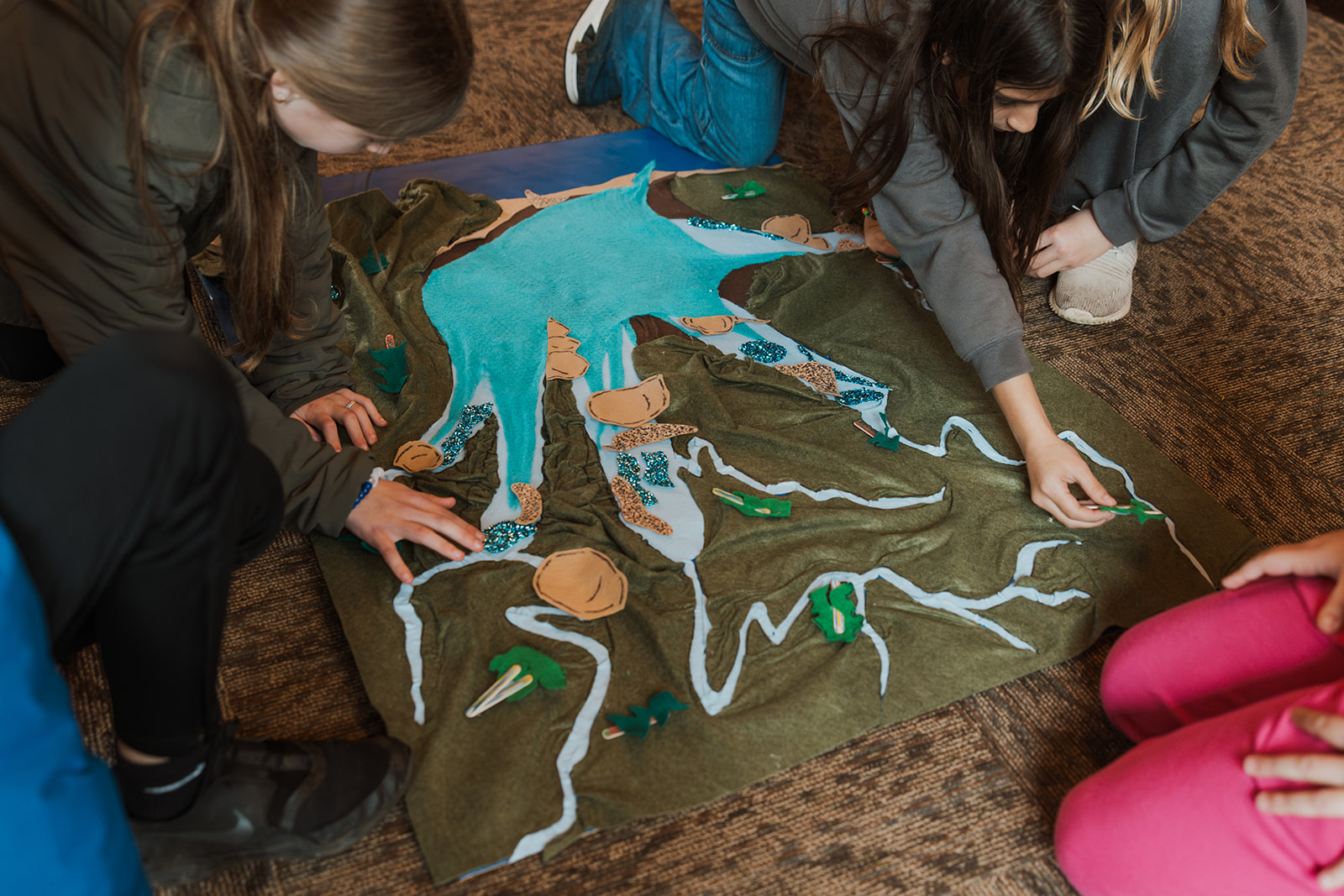 Children play felt logs onto felt map of the watershed
