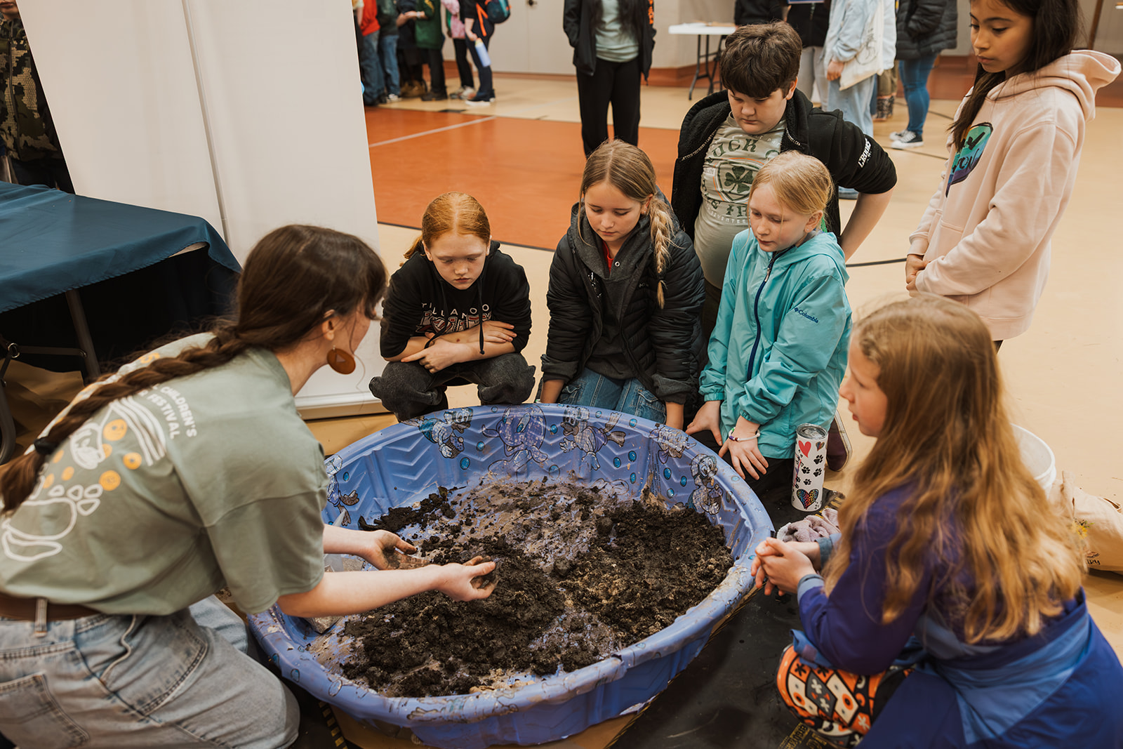 volunteer shows group of students soil being help in plastic kiddie pool