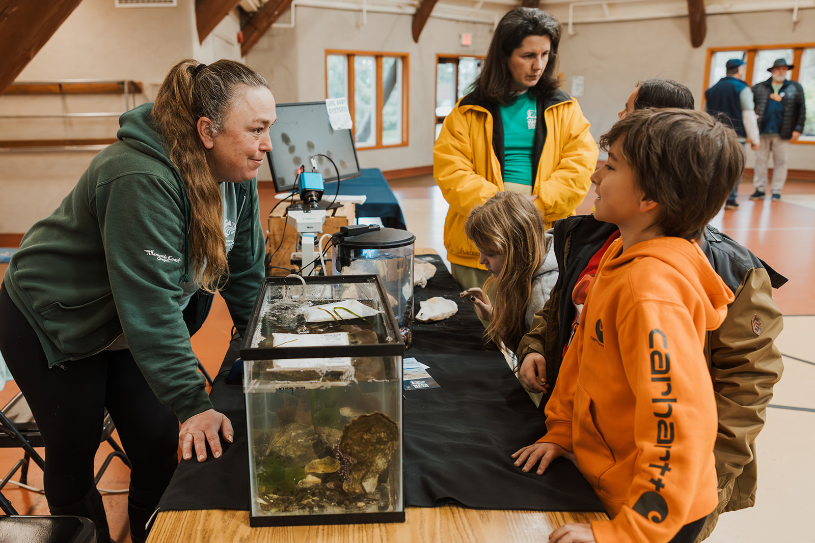 volunteer teaching students about tanks filled with marine animals on the table